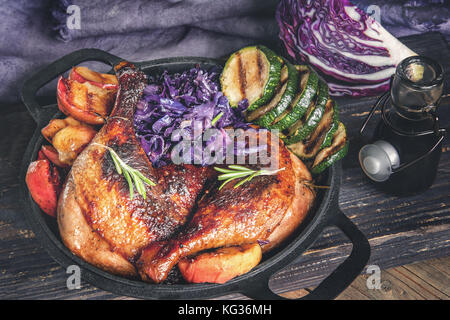 Marinata di pezzi di anatra alla griglia con cavolo rosso, cipolle e mele alla griglia e servita in stile rustico. Foto Stock