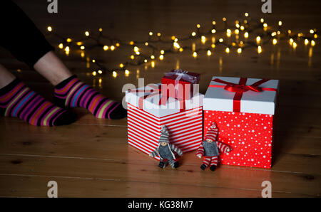 Rosso confezioni regalo i piedi e le luci di Natale sul pavimento in legno Foto Stock