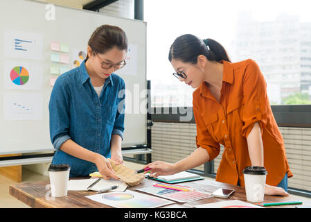 Piuttosto attraente assistente femmina holding strumento di tavolozza mostra per designer manager per scegliere il colore adatto per la nuova società prodotto. Foto Stock