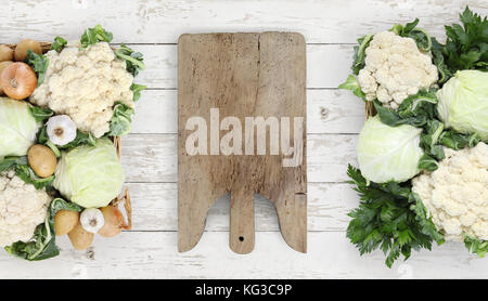 Mangiare sano concetto tagliere di legno con cestello verdure cavolo e cavolfiore cucina sul piano bianco, copia spazio, vista dall'alto Foto Stock