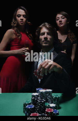 L uomo alla roulette tavolo circondato da belle donne Foto Stock