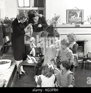 Degli anni Cinquanta, storico, giovani bambini in età prescolare presso un playgroup classe guardando un racconto di burattini su una stringa utilizzata dagli insegnanti di sesso femminile, Inghilterra, Regno Unito. Foto Stock