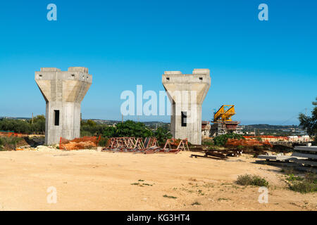 Autostrada autostrada o costruzione di ponti con grandi gantry gru di sollevamento in tratti di strada tra pilastri. Sicilia, Italia Foto Stock