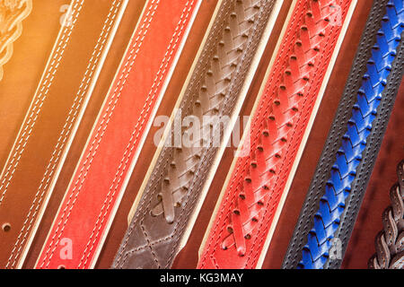 Un close-up di nastri stretti in vera rosso, blu e pelle marrone. pattern fatta di cinghie di cuoio Foto Stock