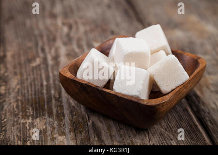 Lo zucchero in una ciotola di legno su un vecchio sfondo di legno Foto Stock