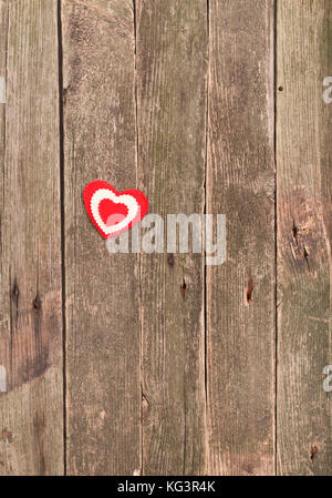 Cuore su vecchie schede madri. una figura da tessuto a forma di cuore sul vecchio diventare non verniciata di colore grigio di tavole di legno Foto Stock