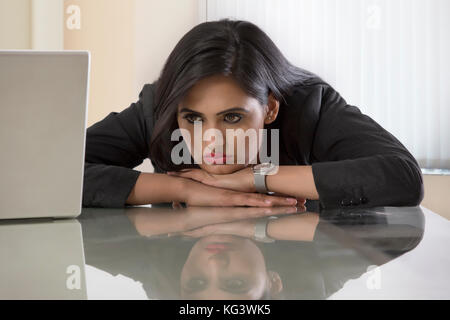 Sottolineato imprenditrici nel posto di lavoro con il lato stampato rivolto verso il basso sulla parte superiore del banco Foto Stock