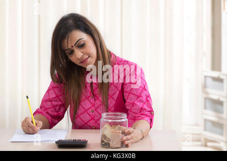 Donna con scatola di denaro il calcolo di fatture Foto Stock