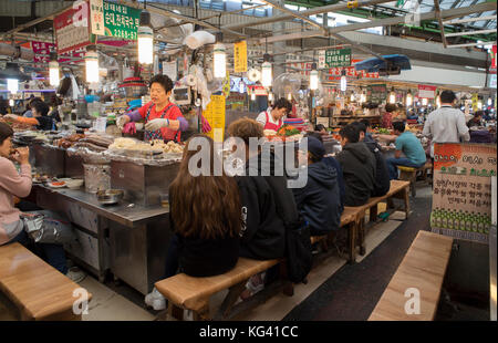 Foodstall nel mercato Gwangjang a Seul, Corea del Sud che serve tradizionali gnocchi di patate, kimchi e altri autentica Cucina Coreana Foto Stock