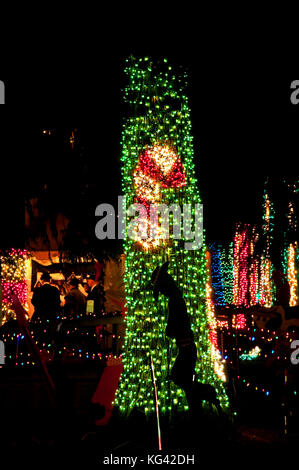 Questa vacanza verticale stock immagine è rossa e bianca a strisce candy cane contro verde le luci di Natale su un albero con un cowboy immagine ritagliata nella parte anteriore. Foto Stock