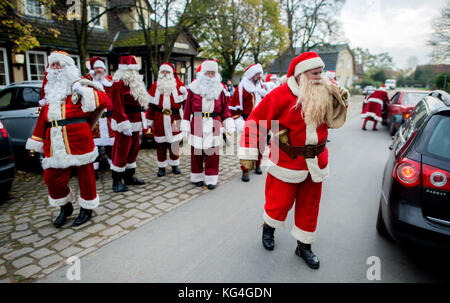 Celle, Germania. 4 novembre 2017. Numerosi imitatori di Babbo Natale possono essere visti per strada a Garssen, un quartiere di celle, Germania, il 4 novembre 2017. Da più di dieci anni, il sosia di Babbo Natale, Willi Dahmen, offre un corso di formazione per gli impersonatori di Babbo Natale e Angelo di Natale. I partecipanti impareranno anche a conoscere il codice onorario degli imitatori di Babbo Natale. Crediti: Hauke-Christian Dittrich/dpa/Alamy Live News Foto Stock