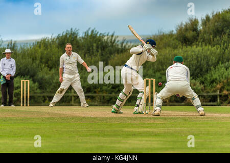 Un battitore gioca un colpo durante una domenica League match tra due locali squadre di cricket. Foto Stock