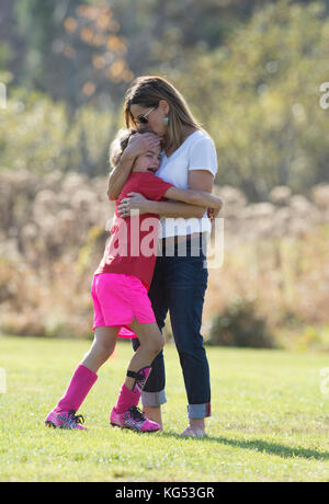 Un 6yr. old girl giocando in una partita di calcio è consolato da sua madre in seguito essere male. waterbury, Vermont, USA Foto Stock