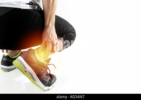 Runner sportivo tenendo la caviglia nel dolore con rotte ritorto in esecuzione congiunta di lesioni sportive e atletico uomo toccando il piede a causa di distorsione su sfondo bianco Foto Stock