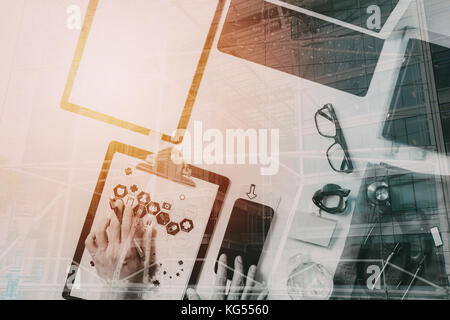 Vista superiore della smart medico lavora con il telefono cellulare e il computer portatile e di uno stetoscopio in legno scuro, scrivania con la costruzione di esposizione Foto Stock