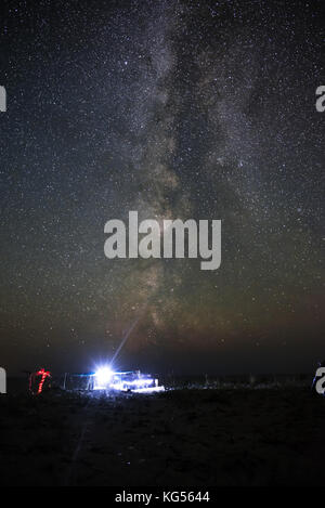 Tenda illuminata sulla spiaggia sullo sfondo di un cielo luminoso con via lattea. Foto Stock