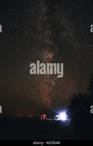 Tenda illuminata sulla spiaggia sullo sfondo di un cielo luminoso con via lattea. Foto Stock