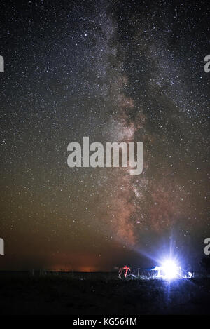 Tenda illuminata sulla spiaggia sullo sfondo di un cielo luminoso con via lattea. Foto Stock