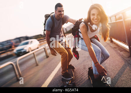 Giovane coppia attraente skateboard equitazione e divertimento Foto Stock