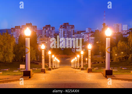 Scale e luminose lampioni di zavokzalnyy complesso memoriale sullo sfondo di edifici di appartamenti al crepuscolo, Sochi, Russia Foto Stock