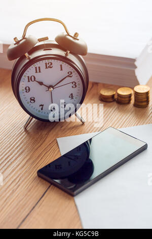 Le ore di lavoro, vintage orologio e telefono cellulare su ufficio business desk Foto Stock