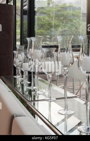 Bicchieri in cristallo con candele in stand by una grande finestra. Foto Stock