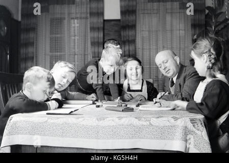Membri di una famiglia con molti bambini mentre si svolgono i compiti, impero tedesco degli anni trenta. Membri DI una famiglia estesa che fa il lavoro, la Germania anni trenta Foto Stock