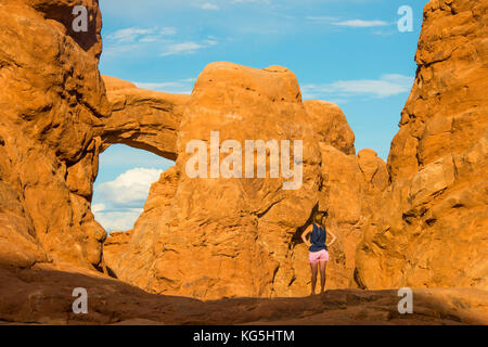 Finestra sud arch visto da una ragazza attraverso la torretta arch, Arches National Park, Utah, Stati Uniti d'America Foto Stock