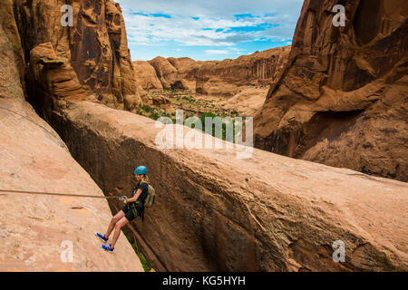 Donna rapelling giù un arco gigante, canyonering, Moab, Utah, Stati Uniti d'America Foto Stock