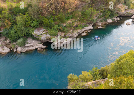 Le acque turchesi e cristalline del fiume Neretva e una piccola imbarcazione per turisti, Mostar, Federazione di Bosnia ed Erzegovina Foto Stock