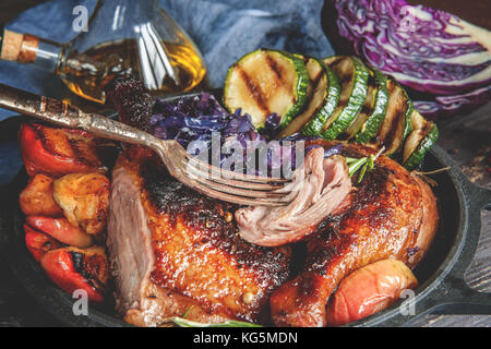 Marinata di pezzi di anatra alla griglia con arrosto cavolo rosso, cipolla e mele alla griglia e servita in stile rustico. Messa a fuoco selettiva. Foto Stock