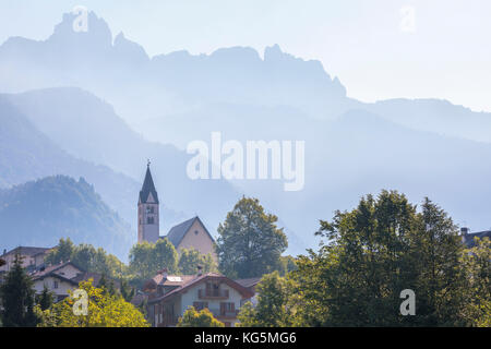 L'Europa, Italia, veneto, Belluno. La Valle Agordina con la chiesa principale e Tamer del Moschesin montagne sullo sfondo Foto Stock