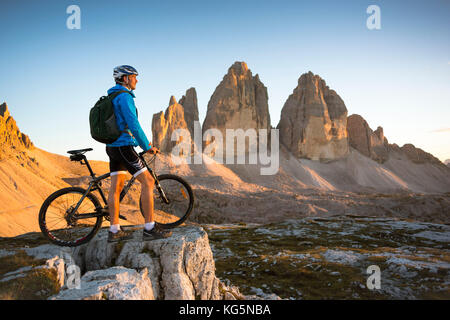 Un ciclista sta guardando il tramonto di fronte alle tre cime di lavaredo, provincia di Belluno, Veneto, Italia Foto Stock