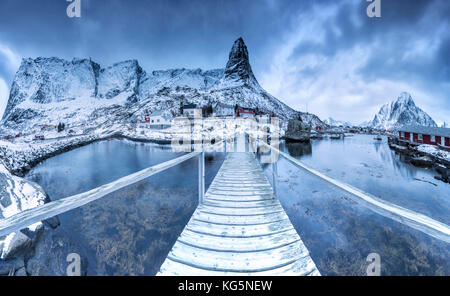 Un ponte sul freddo del mare collega un tipico villaggio di pescatori. Isole Lofoten Norvegia settentrionale Europa Foto Stock