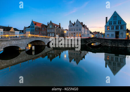 Le luci del tramonto su edifici storici del centro città si riflette nei tipici canali di Bruges Fiandre Ovest Europa Belgio Foto Stock