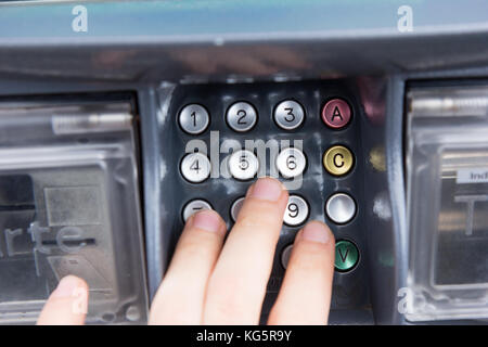 Una mano premendo un codice PIN per un bonifico bancario con una carta di credito. Foto Stock