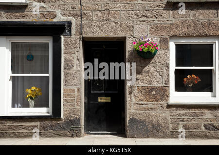 Fiori adornano le finestre e un muro di una casa in SAINT JUST, Cornwall, Inghilterra Foto Stock