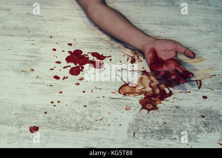 La mano nel sangue su un pavimento bianco. concetto foto di omicidio e di criminalità. giovani il corpo dell uomo sul pavimento con la sanguinosa di ferite e di sangue sul suo braccio e vicino a f Foto Stock