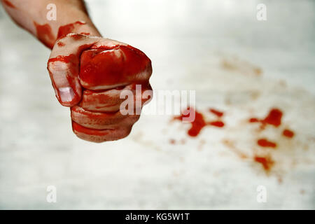 A pugni con sangue. fighter. pugno sangue closeup sullo sfondo delle gocce di sangue sul pavimento. fighter fighter mostra una sanguinosa mano piegata in un fi Foto Stock