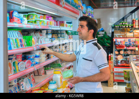 Far provincia, Shiraz, Iran - 20 aprile, 2017: uno sconosciuto di mezza età iraniano che considera gli elementi di generi alimentari sul negozio di alimentari ripiano. Foto Stock