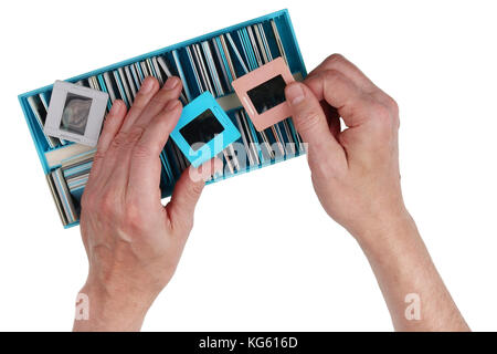 Un anziano uomo nostalgico guarda attraverso la vecchia pellicola diapositive a colori da una famiglia archivio fotografico. isolato su bianco concetto studio shot Foto Stock