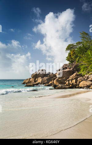 La Seychelles, Praslin, Anse Georgette, spiaggia uomo seduto sulle rocce al bordo della spiaggia Foto Stock