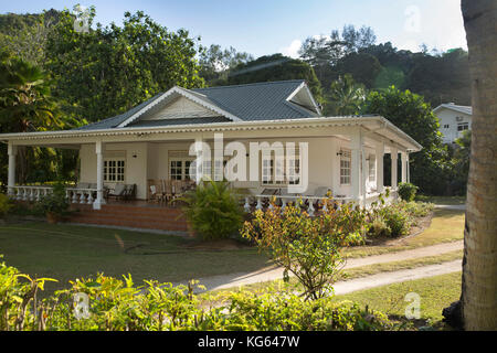 La Seychelles, Praslin, Grand Anse, stile coloniale bungalow con veranda in giardino tropicale Foto Stock