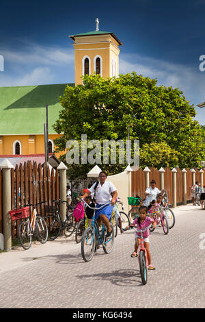 La Seychelles, La Digue, La Passe, bambini lasciando Église de Notre Dame de l'Assomption scuola su biciclette Foto Stock