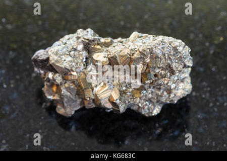 Le riprese in modalità macro di minerale naturale campione di roccia - ruvida di pirite di ferro sulla pietra di granito scuro sfondo dal Messico Foto Stock