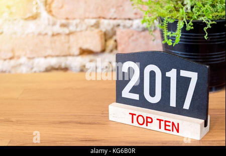 Anno Nuovo 2017 top ten argomento numero sulla lavagna segno e pianta verde sulla tavola di legno in corrispondenza di un muro di mattoni. Foto Stock