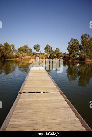 Il molo di legno nel lago con alberi florest scenario dello sfondo. Foto Stock