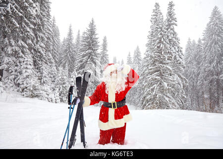 Babbo Natale sciatore con sci nei boschi in inverno a Natale. Foto Stock