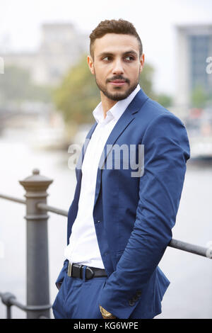 Bello dai capelli scuri permanente imprenditore dal fiume Foto Stock