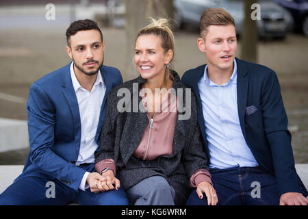 Una donna e due uomini in abiti seduta sul banco compresi Foto Stock